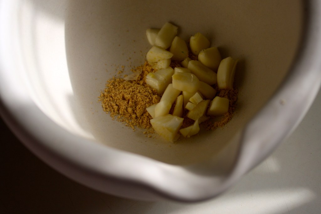 Add chopped garlic and grind some more.