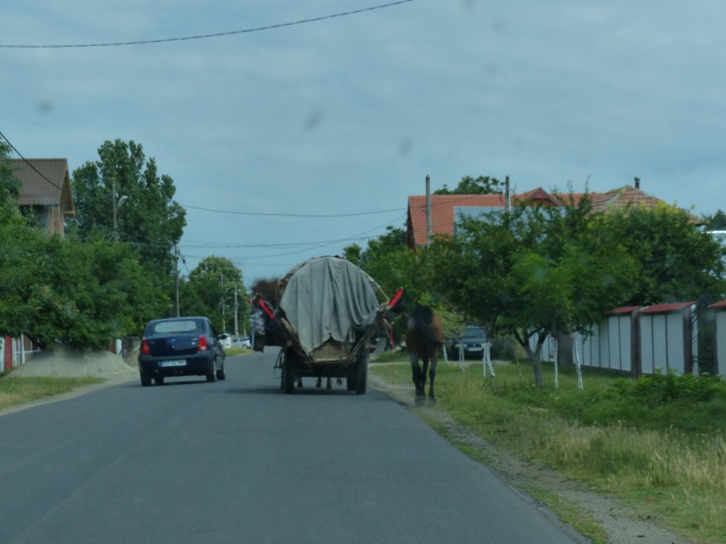A gypsy wagon being passed on the left. No sidewalks. No shoulder. Lots of pedestrians and kids playing along the road.
